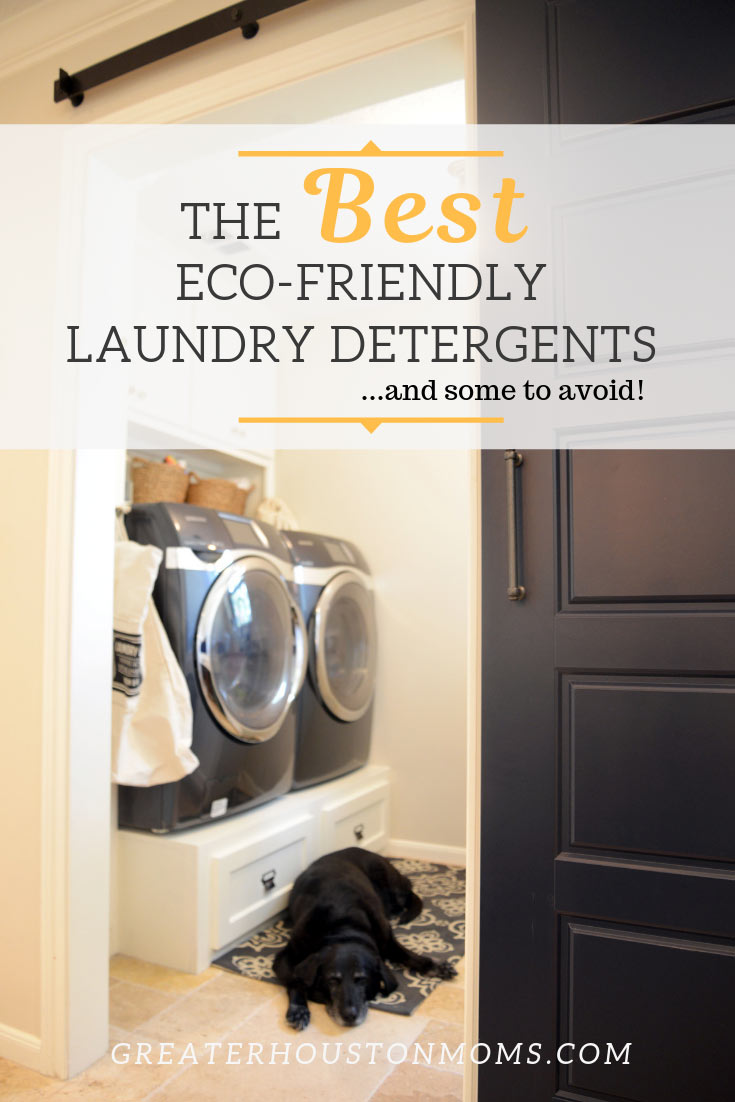 Vertical photo of a light and airy laundry room with navy washer and dryer, white painted paneling, a navy sliding barn door, and a black lab sleeping on a ikat rug