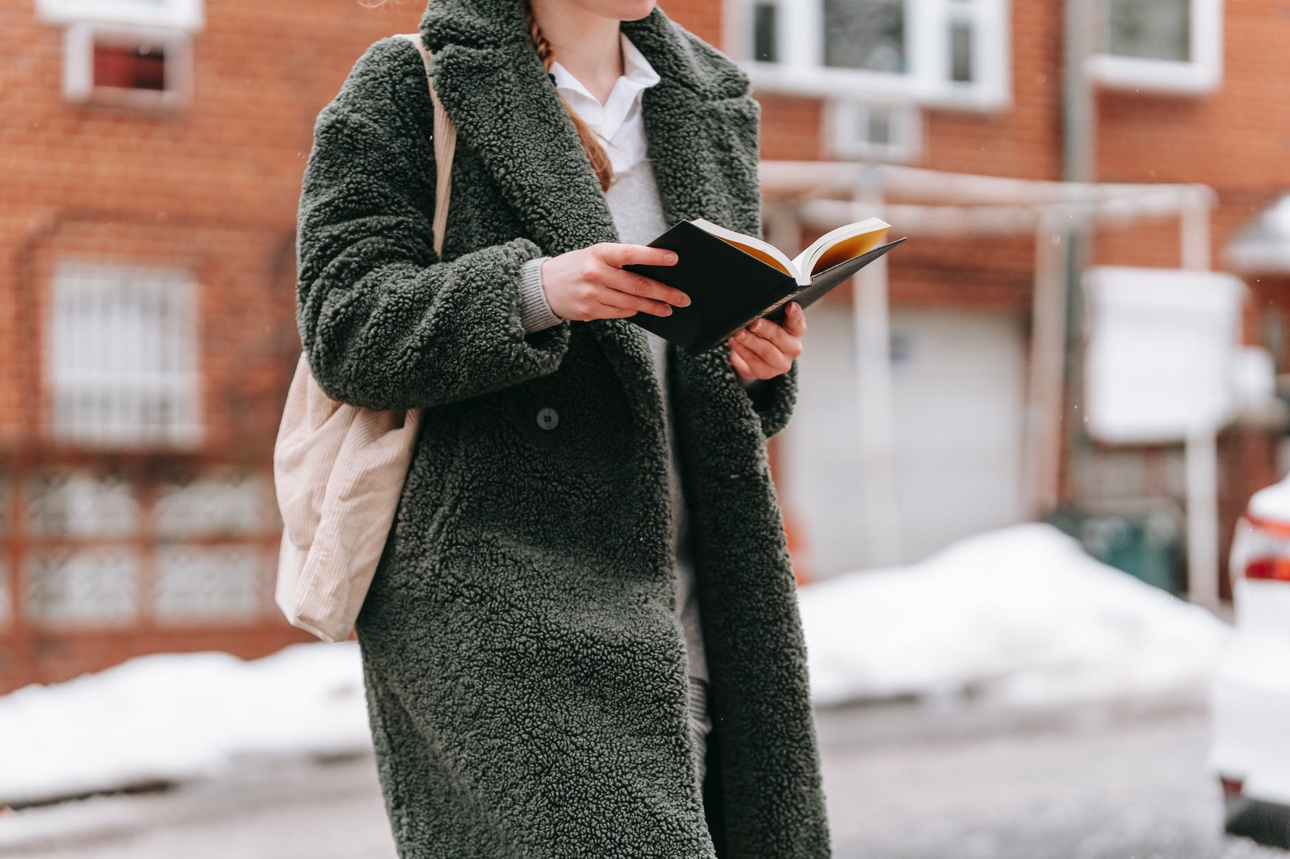 crop student reading book in winter town