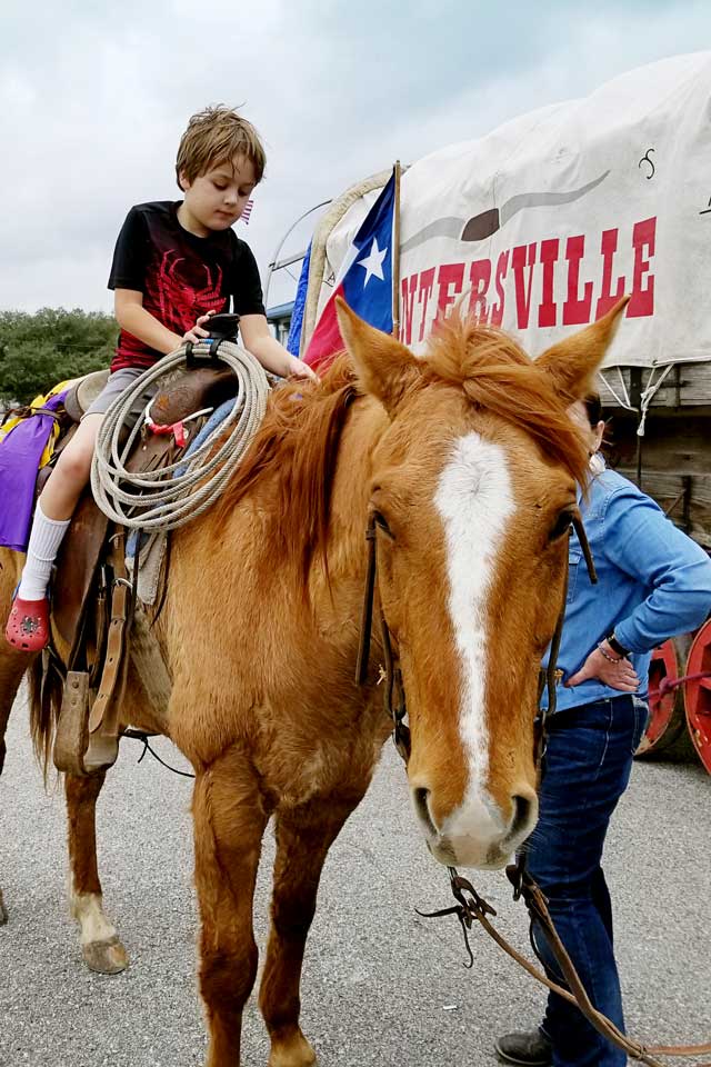 Houston Rodeo trail riders stop and let a little boy and other children sit on their horses in Tomball Texas.