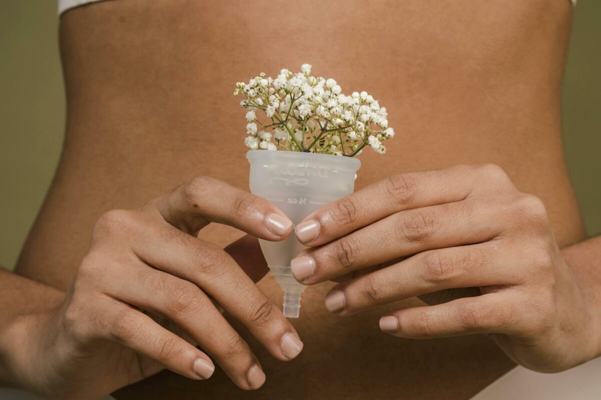 A creative depiction of femininity with a menstrual cup and flowers, emphasizing health and intimacy.